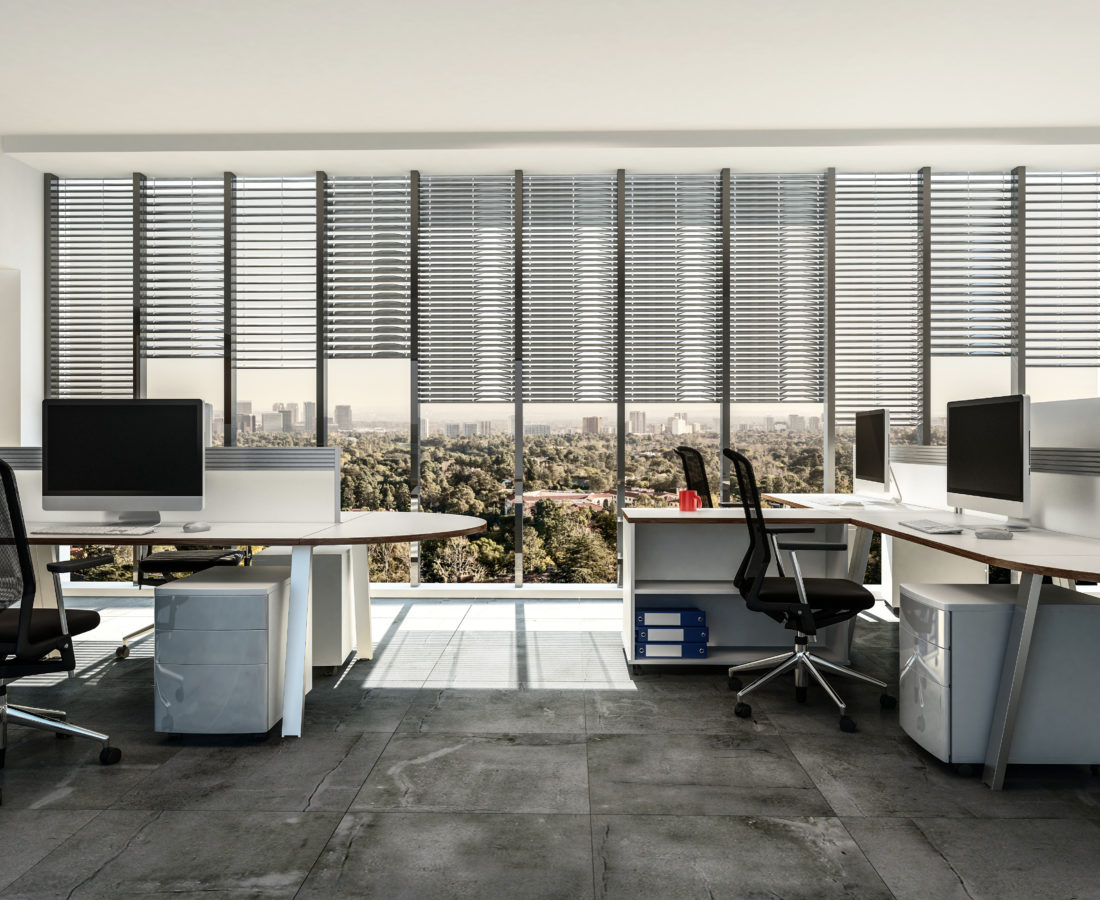 Modern business office with multiple workstations around table style desks with cabinets, tiled grey floor and large windows with blinds. 3d render